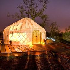 a yurt is lit up at night on a deck