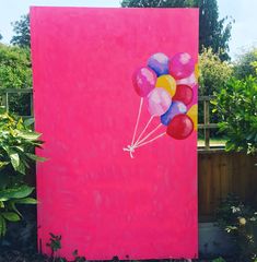 there is a painting on the side of a pink building with balloons painted on it