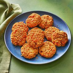 a blue plate topped with carrot patties on top of a green tablecloth next to a napkin