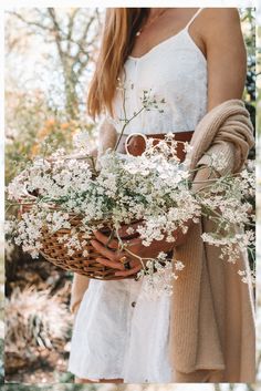 a woman holding a basket filled with white flowers