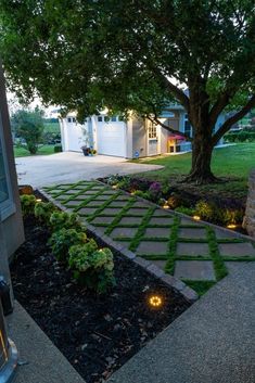 an outdoor walkway with lights in the grass and trees around it, leading to a house