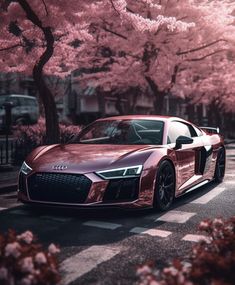 a black car parked on the side of a road next to trees with pink flowers