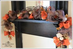 an orange and brown wreath is hanging on the mantle