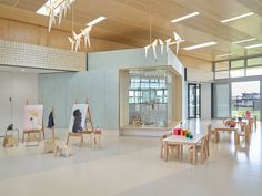 an empty room with tables, chairs and art work on display in the windowed area