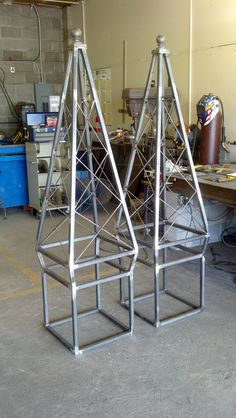 two metal structures sitting on top of a table in a room filled with other items