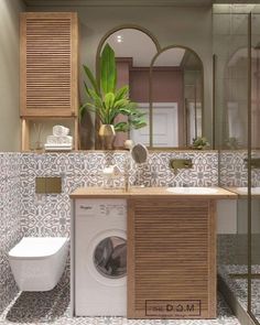 a washer and dryer in a bathroom next to a toilet with a plant