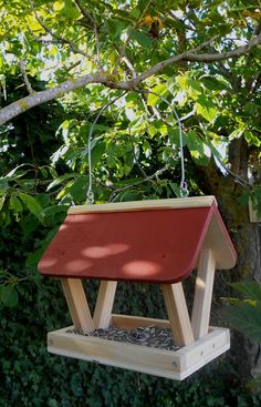 a wooden bird feeder hanging from a tree