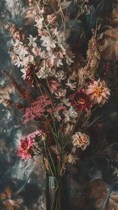 a vase filled with lots of flowers sitting on top of a table next to a wall