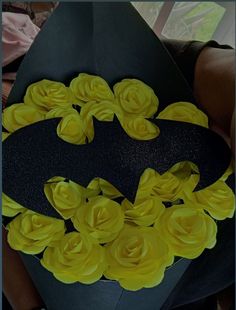 a batman hat with yellow flowers on it and a bat shaped box in the middle