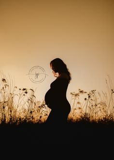 a pregnant woman standing in the grass at sunset with her belly up to her chest