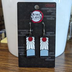 a pair of earrings sitting on top of a wooden table next to a white container