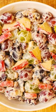 a white bowl filled with fruit salad on top of a wooden table