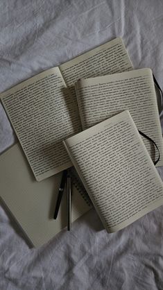 three open books sitting on top of a bed