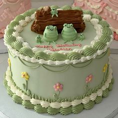 there is a green cake with two frogs on it