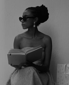 a woman wearing sunglasses is reading a book