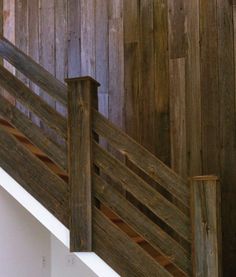 a cat sitting on the edge of a wooden stair case in front of a wood paneled wall