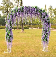 an outdoor wedding ceremony with purple and green flowers on the arch, in front of a tree