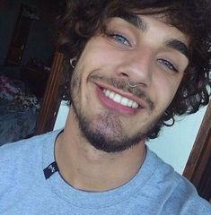 a close up of a person with a beard and piercing on his nose smiling at the camera