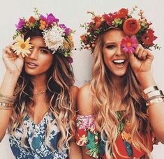 two beautiful women standing next to each other with flowers in their hair and wreaths on their heads