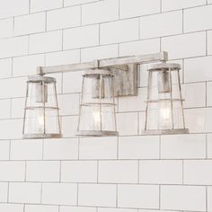 three light fixtures mounted on a white brick wall