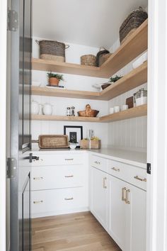 a white kitchen with open shelving and wooden shelves on the wall next to it