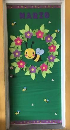 a door decorated with paper flowers and a bee on it's side, that says marzo