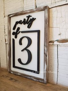 a wooden sign with the number three in black and white, hanging on a wall