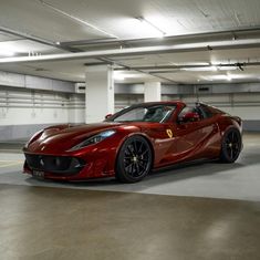 a red sports car is parked in a parking garage with no one around it,