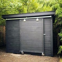 a large gray shed sitting next to a lush green forest