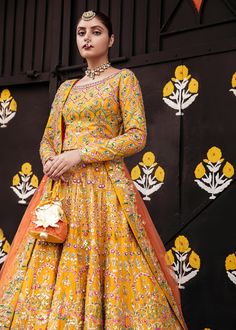 Pakistani Bridal Yellow Orange Lehenga Choli is a traditional masterpiece to wear on any wedding festivity, especially Mehndi or Mayun. The vibrant shade of this Lehenga Choli makes it an alluring choice for the Bride. Hand-crafted adornments and designs make this Mehndi Dress an epitome of beauty and royalty. Choli: Bridal choli in the bright yellow shade is gracefully emblazoned with hand-crafted details of sitara and pearls. The fully embellished choli is adorned with lavish designs and fine Traditional Dola Silk Wedding Gown, Traditional Wedding Gown In Dola Silk, Traditional Wedding Dola Silk Gown, Traditional Kundan Gown For Ceremonies, Traditional Gown With Multicolor Embroidery And Dupatta, Traditional Dola Silk Gown For Festivals, Bollywood Style Wedding Salwar Kameez With Multicolor Embroidery, Traditional Dola Silk Gown, Multicolor Embroidered Raw Silk Anarkali Set For Wedding