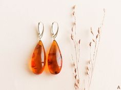 "Natural Baltic amber cognac color earrings are a perfect choice for classy style admirers! Shaped in drop form these earrings look delicate yet fancy. MATERIALS AND SIZE: Stone: 100% Natural Baltic Amber Findings: Sterling silver 925 Earrings A: Weight: 6,4  g (0,22 oz) Bead size: 3,3 cm (1,29  in) x 1,5 cm (0,59 in) Total length: 5,4 cm (2,12 in) Earrings B: Weight: 5,9 g  (0,2 oz) Bead size: 2,9 cm (1,14 in) x 1,4 cm (0,55 in) Total length: 4,9 cm (1,92 in)  PLEASE NOTE: All our amber product Elegant Amber Teardrop Earrings, Elegant Baltic Amber Teardrop Earrings, Elegant Orange Teardrop Earrings, Elegant Brown Teardrop Earrings For Gift, Handmade Teardrop Earrings For Formal Occasions, Light Yellow Color, 925 Earrings, Golden Logo, Cognac Color