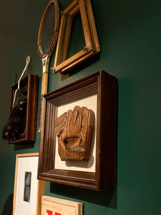 there is a baseball glove hanging on the wall next to pictures and framed memorabilias