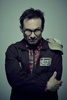 a man wearing glasses and a jacket with his arms crossed