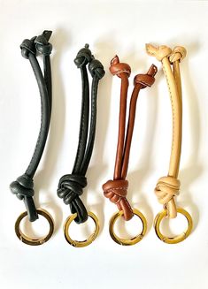 four different colored leather handles with gold rings on each side and black, white, brown, and tan