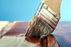 a close up of a paint brush on top of a wooden table with blue sky in the background