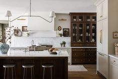 a kitchen with wooden cabinets and marble counter tops, along with bar stools that match the hardwood flooring