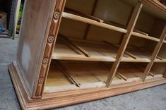 an old wooden cabinet with many shelves and drawers on it's sides, sitting in a garage