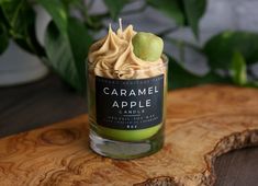 a candle that is sitting on top of a wooden table next to some green leaves