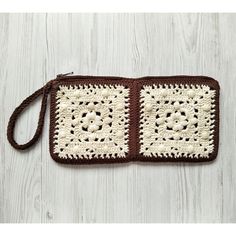 a brown and white crocheted purse on a wooden surface with two squares in the middle