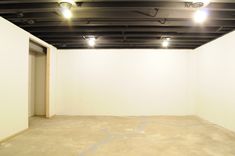 an empty room with white walls and ceiling lights