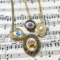 Choice of one vintage necklace or brooch, all in a similar floral or feminine style.  The first necklace is a vintage Avon pendant set with a painted pink and purple flower cab inside a heavy metal surround with flowers above and below. Pendant is in excellent vintage condition, no wear to the gold tone finish, chain measures 17in.  The second necklace is a heart shaped locket with a white cab with blue flowers, on a 28in chain. The last necklace is a lovely oval locket with a faux pearl on a 23in chain.  Brooch is a handmade decoupage piece with the makers initials and the year on the back. Measures 1.5in x 1.25in. In good vintage condition, finish has some wear, glue on top has some yellowing, see photos for details.  Comes packed in a Kraft gift box for convenient gifting. Want to see m Gold Flower Necklace With Vintage Charm, Vintage Antique Gold Necklace Gift, Ornate Locket Brooches For Gifts, Vintage Gold Flower Necklace, Vintage Locket Necklaces As Gifts, Vintage Flower Pendant Locket Necklace, Victorian Pendant Necklace With Brooch Detail, Vintage Flower Jewelry Collectible, Vintage Flower Jewelry For Collectors