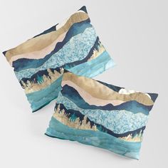 two blue and gold pillows with mountains on them