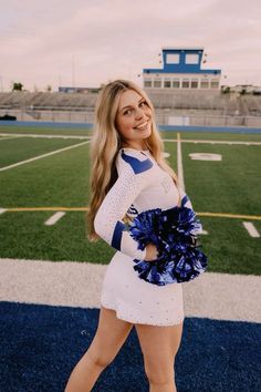 a cheerleader is posing for a photo on the football field with her pom poms