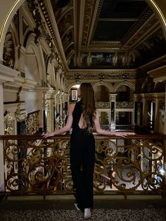 a woman standing on top of a balcony next to a metal railing and looking at the ceiling