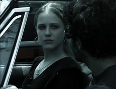 a woman sitting in the back seat of a car with her hair pulled back and wearing large hoop earrings