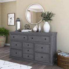 a gray dresser with white vases on top and a mirror above it in a living room