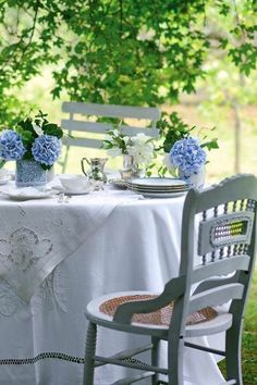 the table is set for two with blue and white flowers in vases