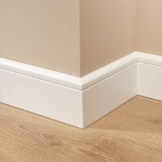 the corner of an empty room with wood flooring and white trim on the walls