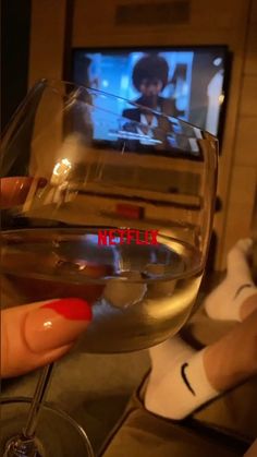 someone holding a wine glass in front of a tv with the words netflix on it