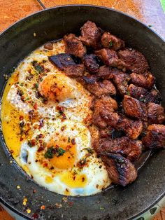 eggs and meat in a skillet on a table